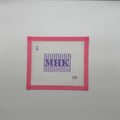 A square white cross-stitch canvas with a pink border, featuring purple embroidered letters 'MHK' inside vertical purple stripes, with a small purple dot and the letters 'CD' near the bottom right, shown on a light gray background.