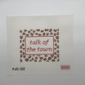 A square needlepoint canvas on white Aida fabric, featuring a leopard-print border in brown and beige with red stitched text reading 'talk of the town' inside a red rectangular frame. The canvas has a small pink brand label in the bottom right corner and the code 'PJ5-122' in black at the bottom left.