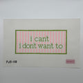 Needlepoint canvas featuring the  text 'i can't i don't want to' in green within a pink striped border, set against a neutral gray background.