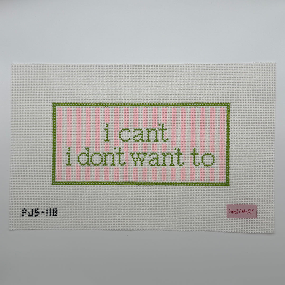 Needlepoint canvas featuring the  text 'i can't i don't want to' in green within a pink striped border, set against a neutral gray background.